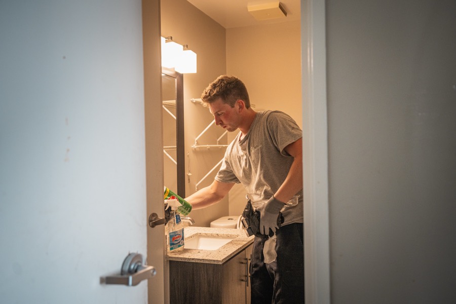 A Complete Junk Removal crew member wiping down a bathroom counter after clearing the room