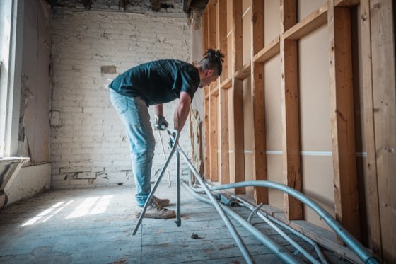 A crew member working in a room stripped back to the bare studs during a demolition
