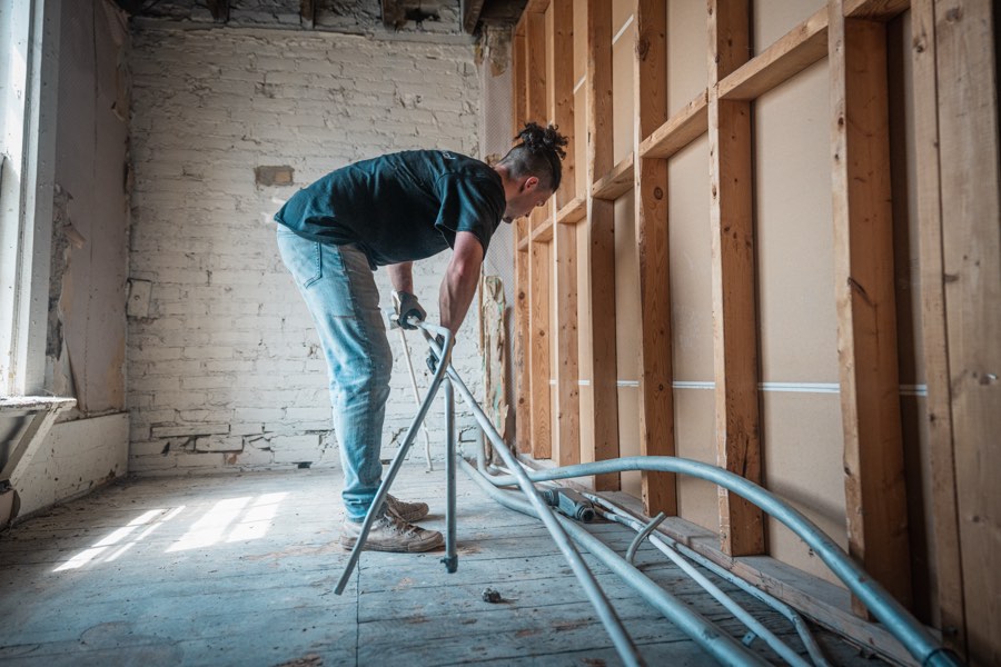 A crew member working in a room stripped back to the bare studs during a demolition